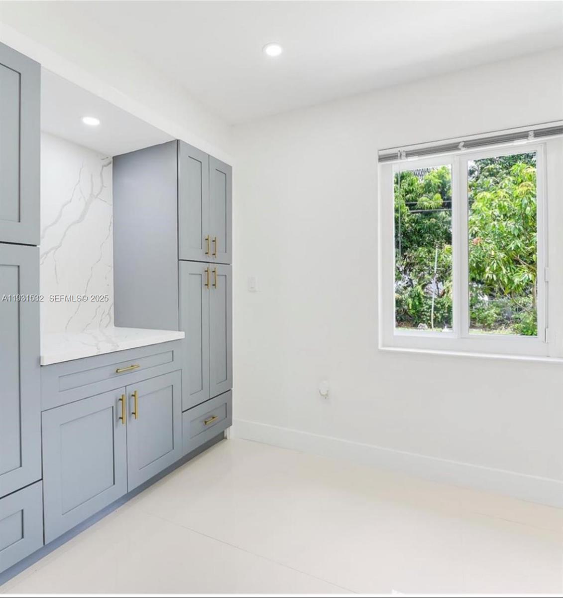 A room features light gray cabinetry, a marble-patterned backsplash, white countertops, and a window view — 851 NW 146th St, Miami FL 33168, MIAMI, FL