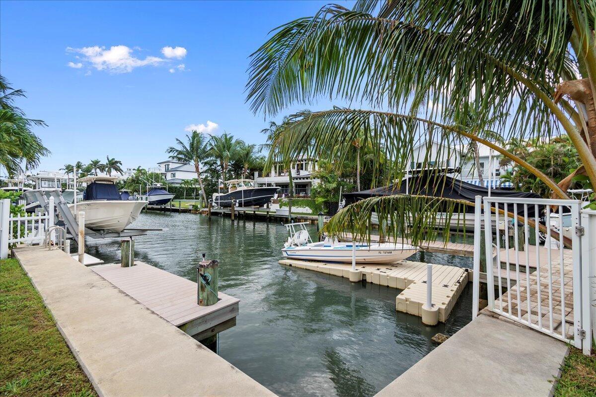 A canal view features multiple boats docked at private piers surrounded by palm trees — 72 Waterway Road, Jupiter FL 33469, JUPITER, FL