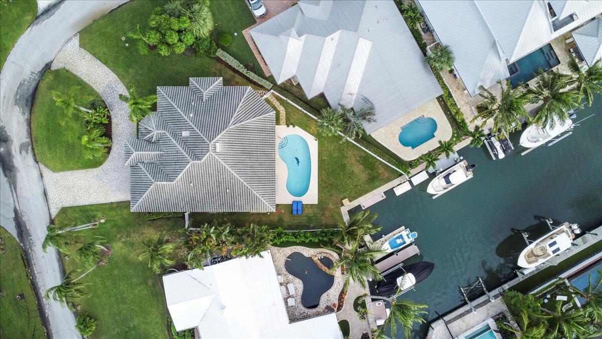 An aerial view shows waterfront homes with swimming pools, boat docks, and moored vessels — 72 Waterway Road, Jupiter FL 33469, JUPITER, FL