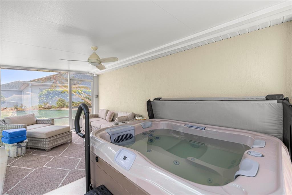 A covered patio features a hot tub, outdoor seating, and a view of a pool — 1492 OLUSTEE PLACE, THE VILLAGES, FL