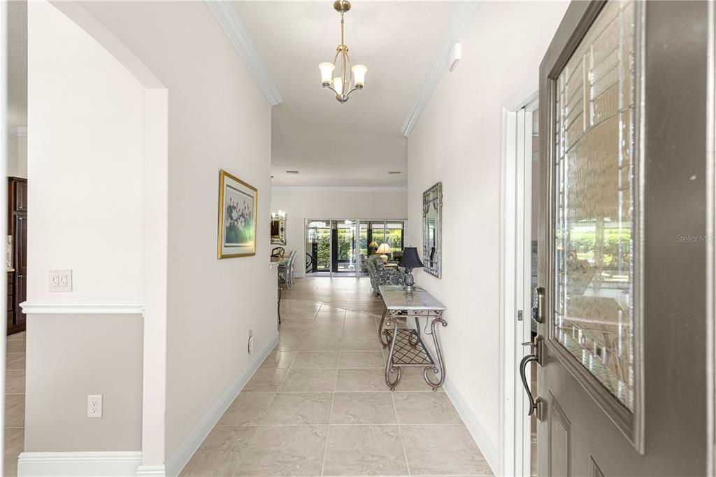 A tiled entryway leads into a bright living area with a view of the patio — 1492 OLUSTEE PLACE, THE VILLAGES, FL