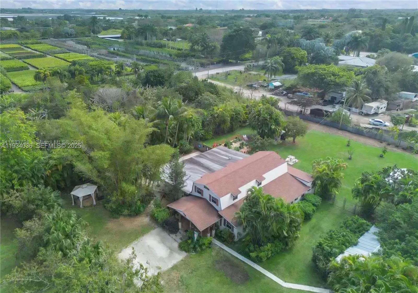 An aerial view shows a two-story house with a brown roof surrounded by lush landscaping — 19810 SW 200th St, Miami FL 33187, MIAMI, FL