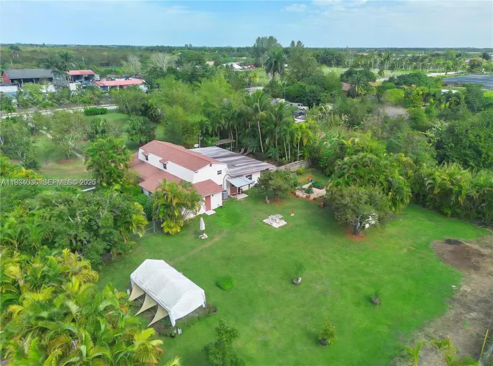An aerial view shows a house with a red roof surrounded by lush green trees — 19810 SW 200th St, Miami FL 33187, MIAMI, FL