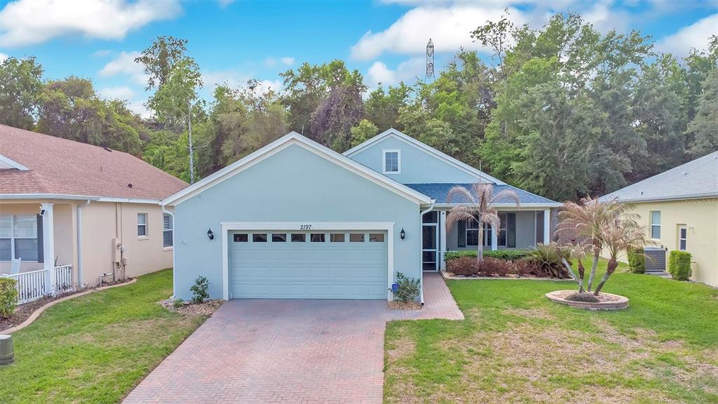 A light blue single-story house with a two-car garage and a brick driveway — 2197 CALEDONIAN STREET, CLERMONT, FL