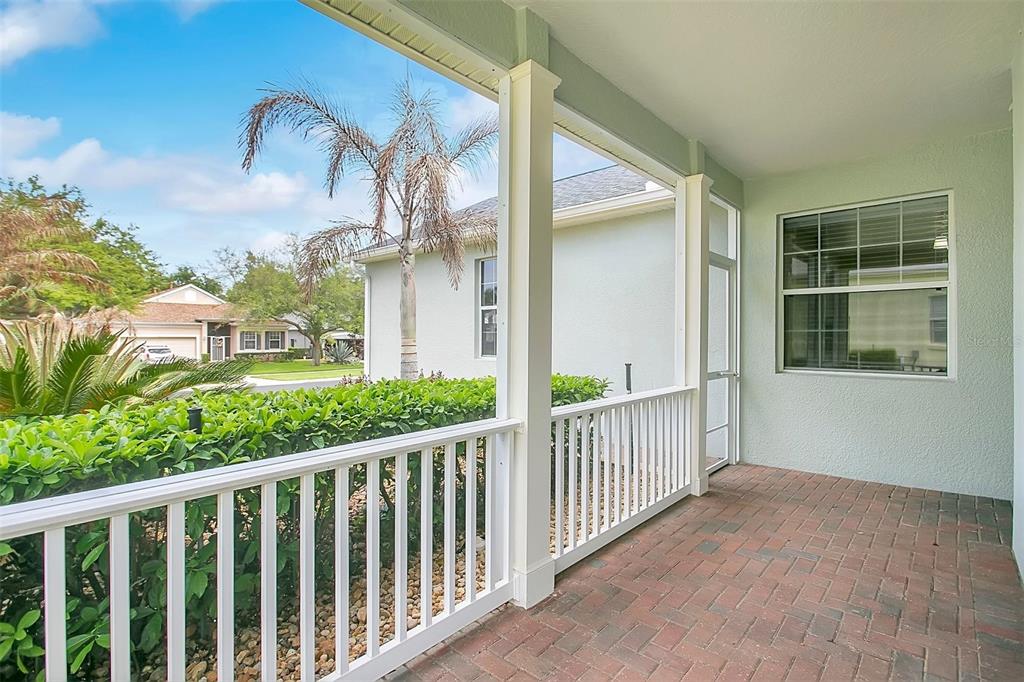 A covered patio with brick pavers, white railings, and a view of a neighboring house — 2197 CALEDONIAN STREET, CLERMONT, FL