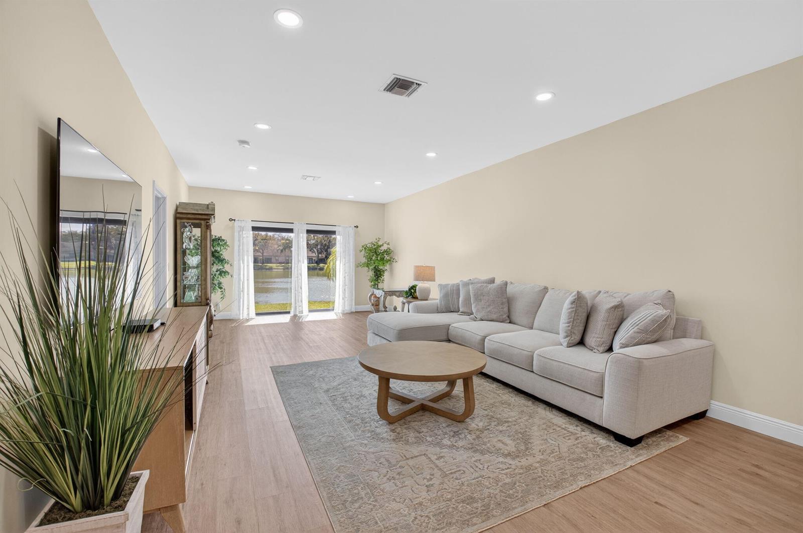 A living room features a sectional sofa, a round coffee table, and a view of water — 8350 Springlake Drive, Boca Raton FL 33496, BOCA RATON, FL