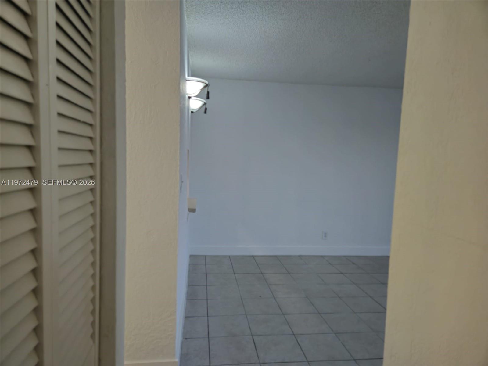 A view through a doorway shows a room with light-colored tile flooring and wall sconces — 4550 NW 9th St # 704E, Miami FL 33126, MIAMI, FL