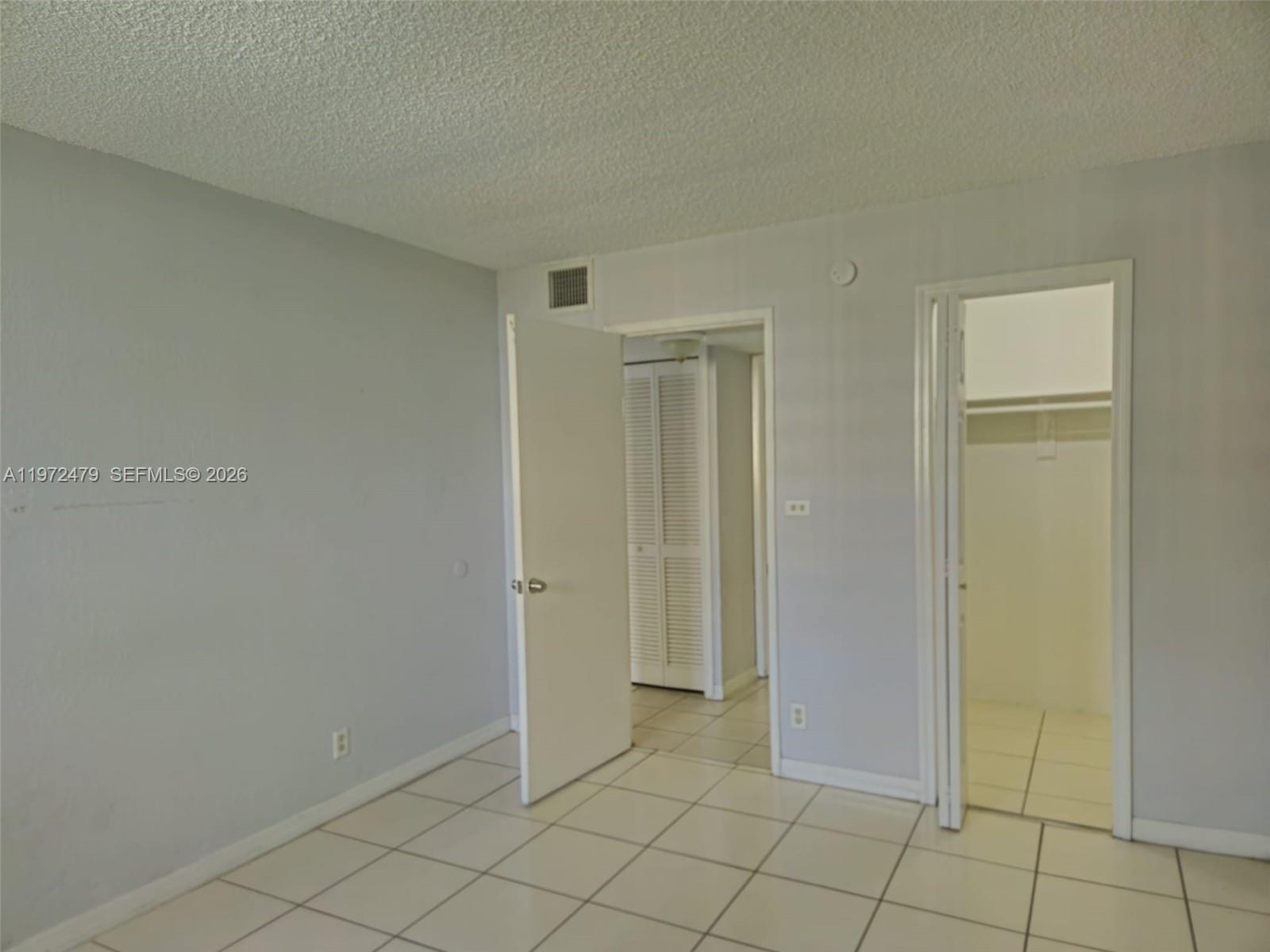 An interior view of a room with light-colored tile flooring, white walls, and two doorways — 4550 NW 9th St # 704E, Miami FL 33126, MIAMI, FL