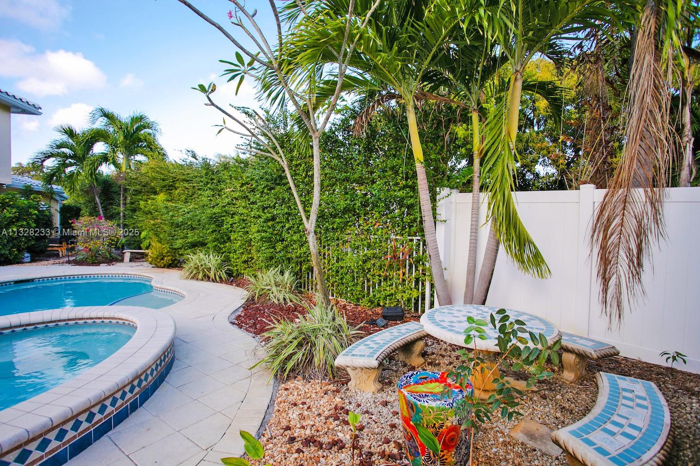 A backyard patio features a swimming pool, tiled seating area, and lush tropical landscaping — 809 S 17th Ave, Hollywood FL 33020, HOLLYWOOD, FL