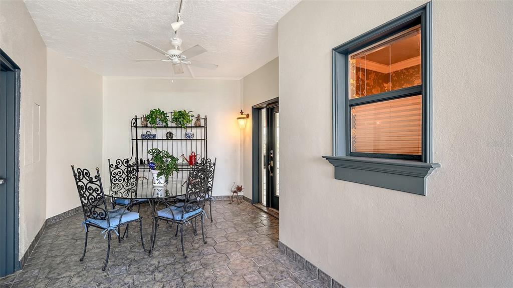A covered patio features a glass-top dining set, tile flooring, and a dark-framed window — 660 GOLDEN GATE POINT UNIT 51 & 52, SARASOTA, FL