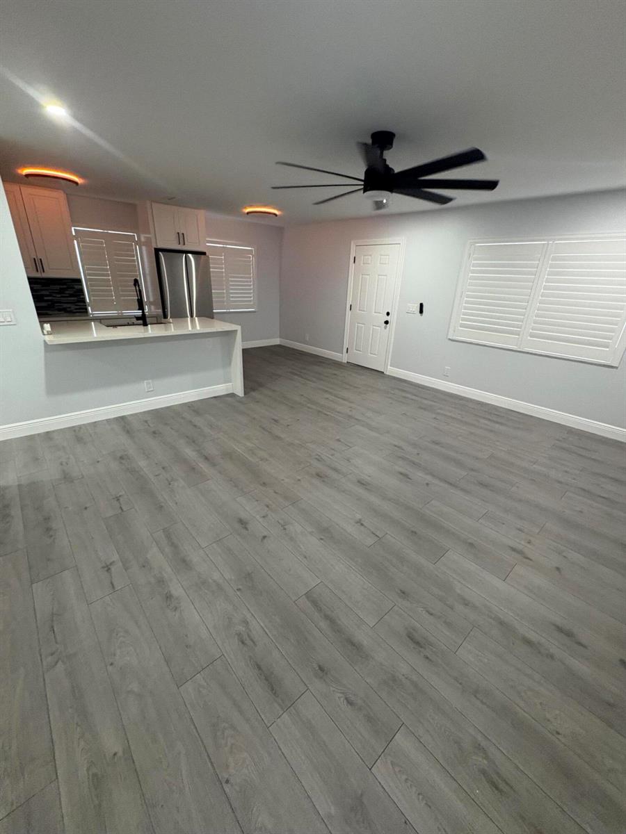 A kitchen with white cabinets and a breakfast bar opens into a living area — 29 Burgundy A, Delray Beach FL 33484, DELRAY BEACH, FL