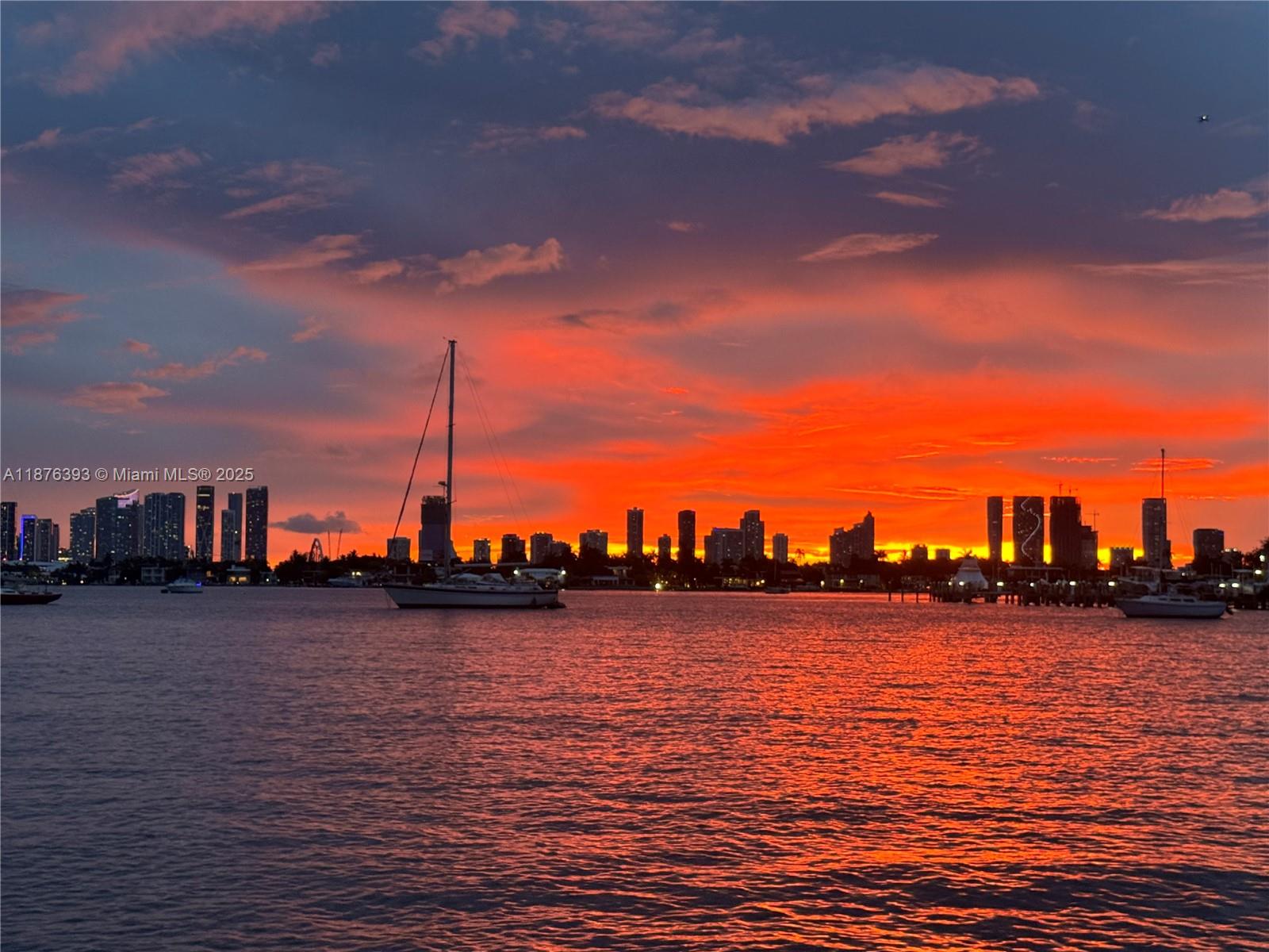 A vibrant sunset illuminates the city skyline across a body of water with sailboats — 1228 West Ave # 312, Miami Beach FL 33139, MIAMI BEACH, FL