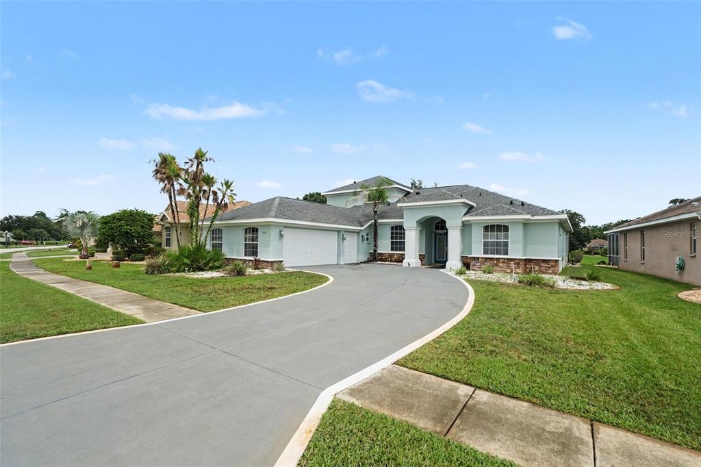 A light blue single-story house with a curved driveway and a stone-accented facade — 5020 GEVALIA DRIVE, BROOKSVILLE, FL