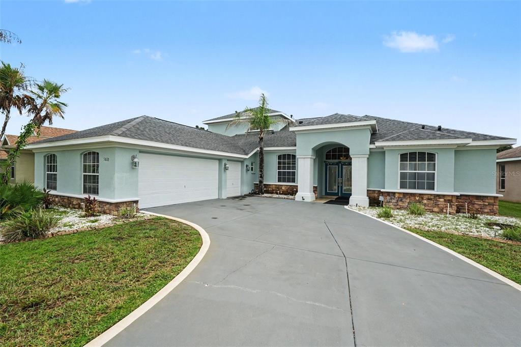 A light blue single-story house features a stone veneer base, a garage, and a driveway — 5020 GEVALIA DRIVE, BROOKSVILLE, FL