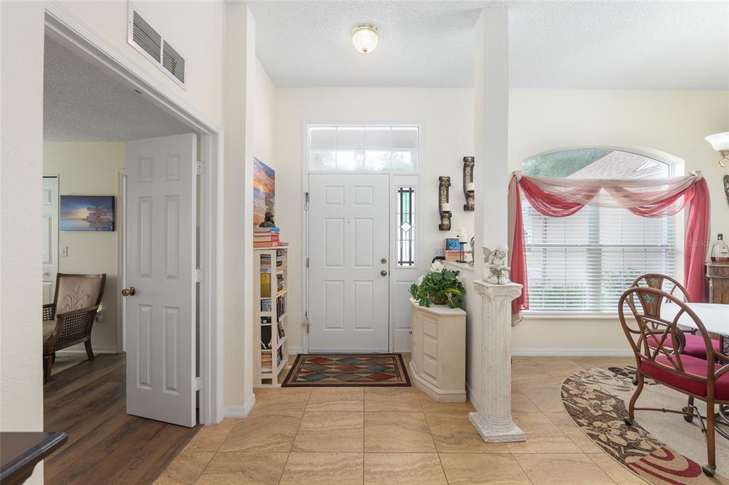 An entryway with tile flooring, a white front door, and a dining area to the right — 11563 SW 74TH COURT, OCALA, FL