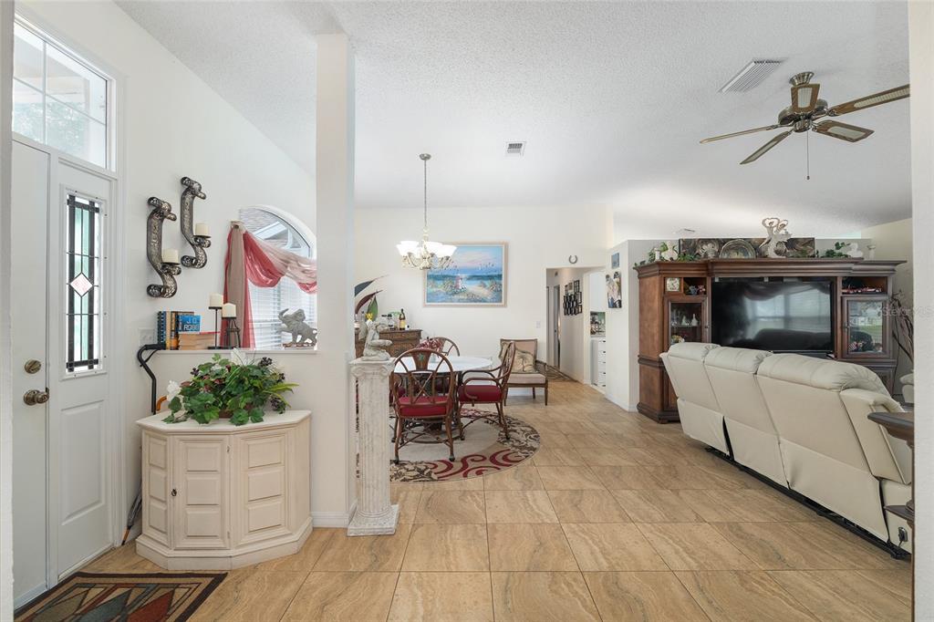 An open-concept living and dining area features tile flooring, a ceiling fan, and neutral walls — 11563 SW 74TH COURT, OCALA, FL