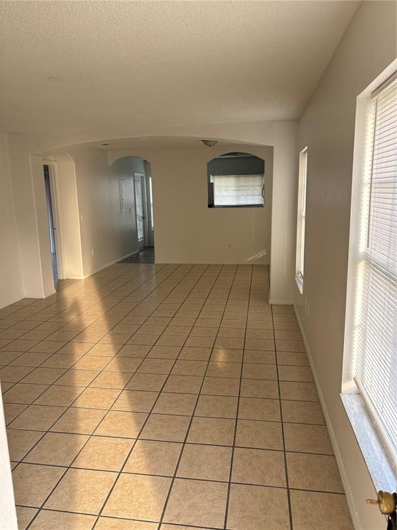 An interior view of a room with light-colored tile flooring and arched wall openings — 13301 FAIRWAY GLEN DRIVE UNIT 104, ORLANDO, FL
