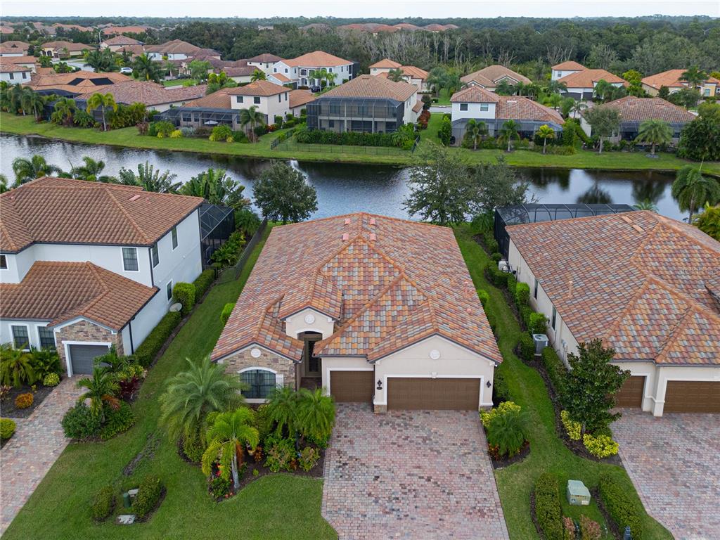 An aerial view shows a suburban house with a tiled roof and a paved driveway — 13423 RAMBLEWOOD TRAIL, BRADENTON, FL