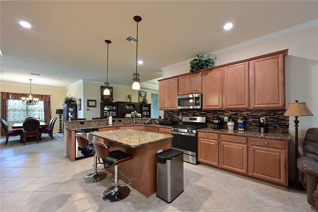 A kitchen with wood cabinets, granite countertops, a center island, and stainless steel appliances — 13423 RAMBLEWOOD TRAIL, BRADENTON, FL