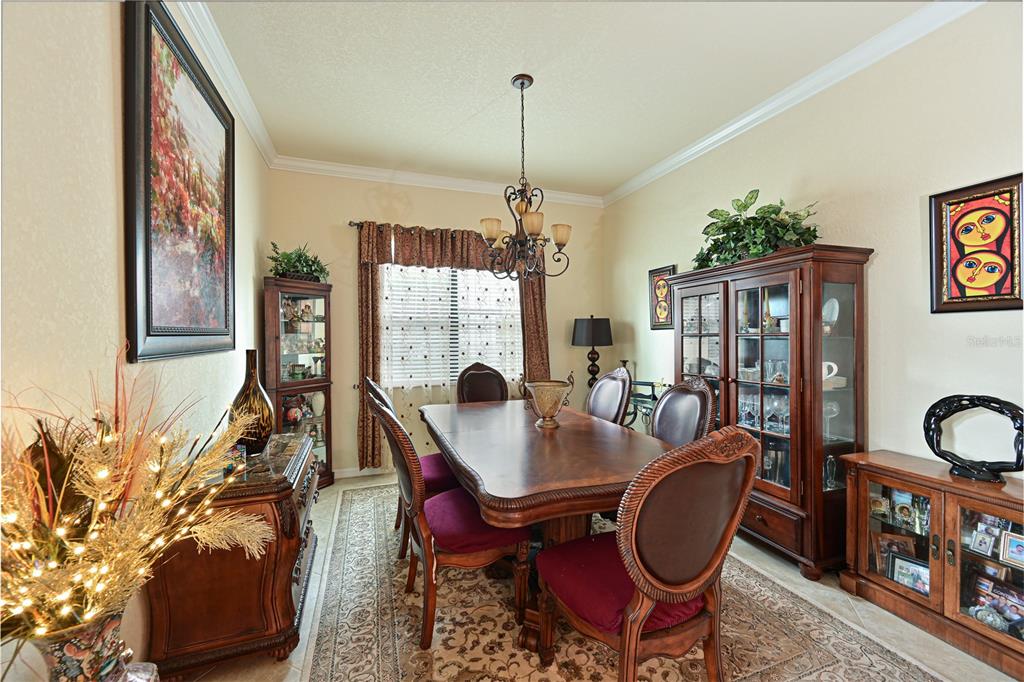 A formal dining room features a wooden table, upholstered chairs, a chandelier, and china cabinets — 13423 RAMBLEWOOD TRAIL, BRADENTON, FL