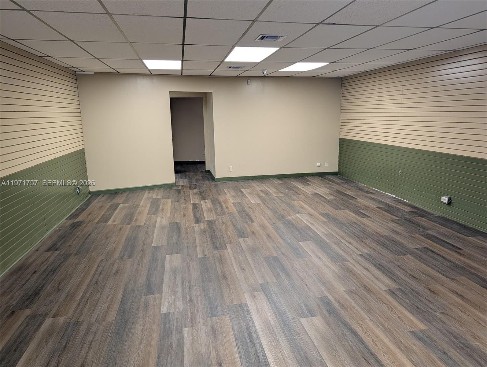 An empty commercial room features wood-look flooring, slat walls, and a drop ceiling — 801 S Dixie Hwy W, Pompano Beach FL 33060, POMPANO BEACH, FL