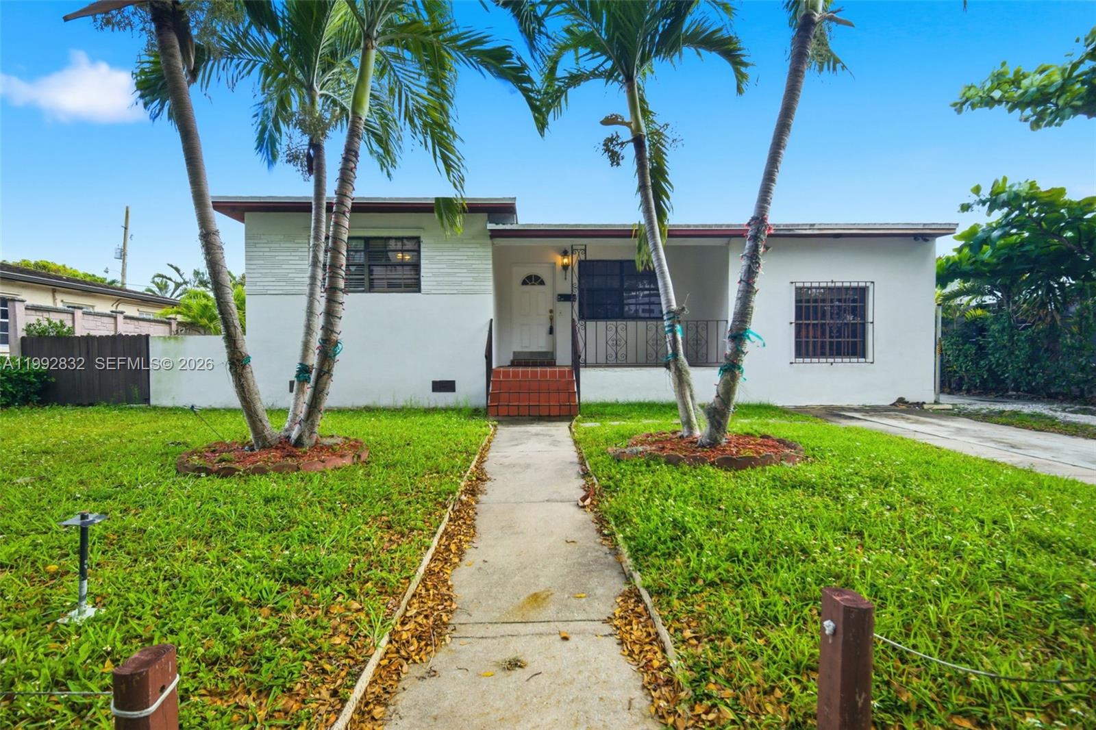 A single-story white house features a front walkway, two palm trees, and a covered porch — 6336 SW 9th St, West Miami FL 33144, WEST MIAMI, FL