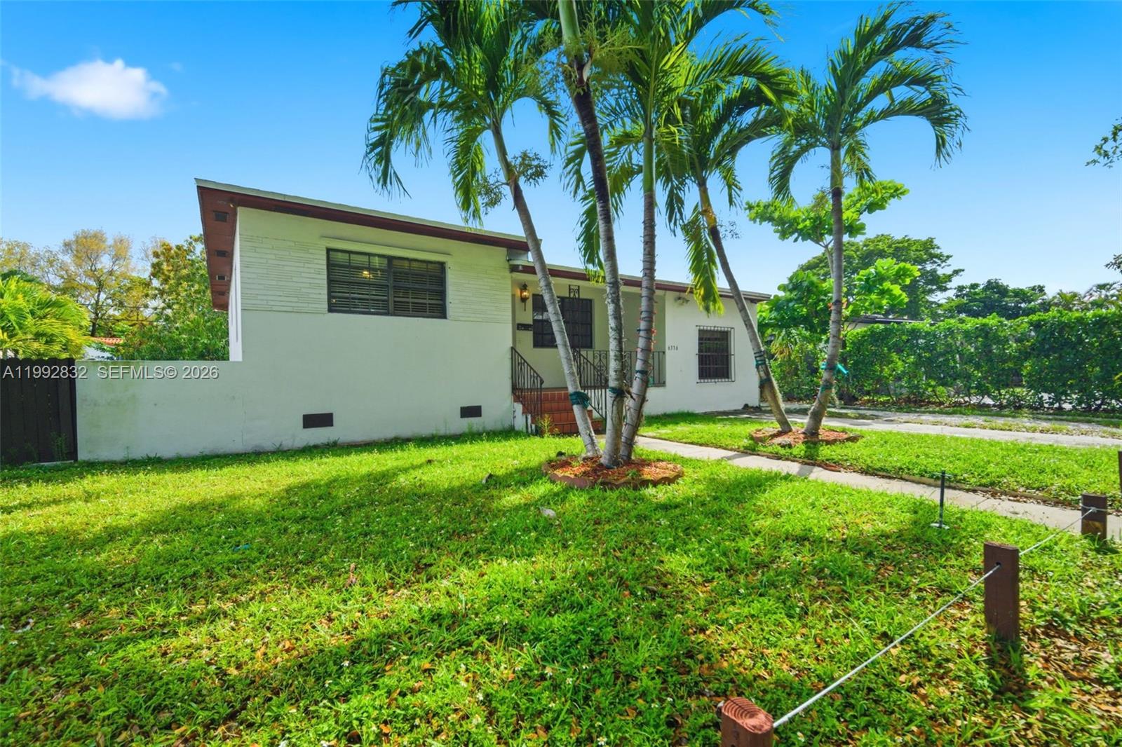 A white single-story house features a front porch, palm trees, and a grassy yard — 6336 SW 9th St, West Miami FL 33144, WEST MIAMI, FL