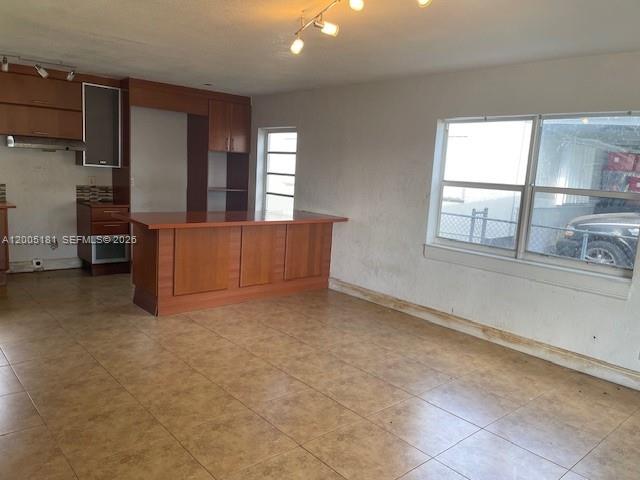 An open-concept kitchen and living area features wood cabinetry, a breakfast bar, and tile flooring — 758 SW 3rd Pl, Dania Beach FL 33004, DANIA BEACH, FL