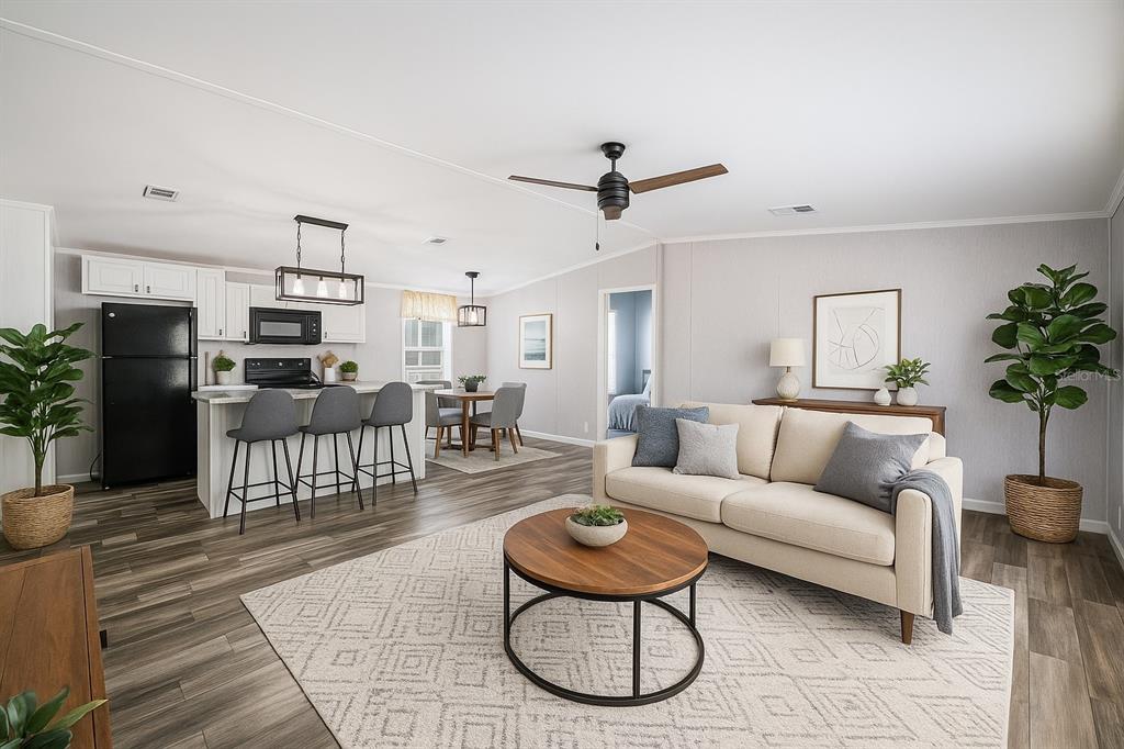 An open-concept living room and kitchen featuring wood-look flooring, a kitchen island, and neutral furniture — 1 BEAVERKILL DRIVE, LAKE WALES, FL