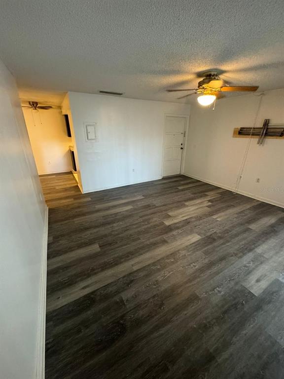 An interior view of a room with gray wood-look flooring and a ceiling fan — 5951 VILLAGE CIRCLE UNIT GE, ORLANDO, FL