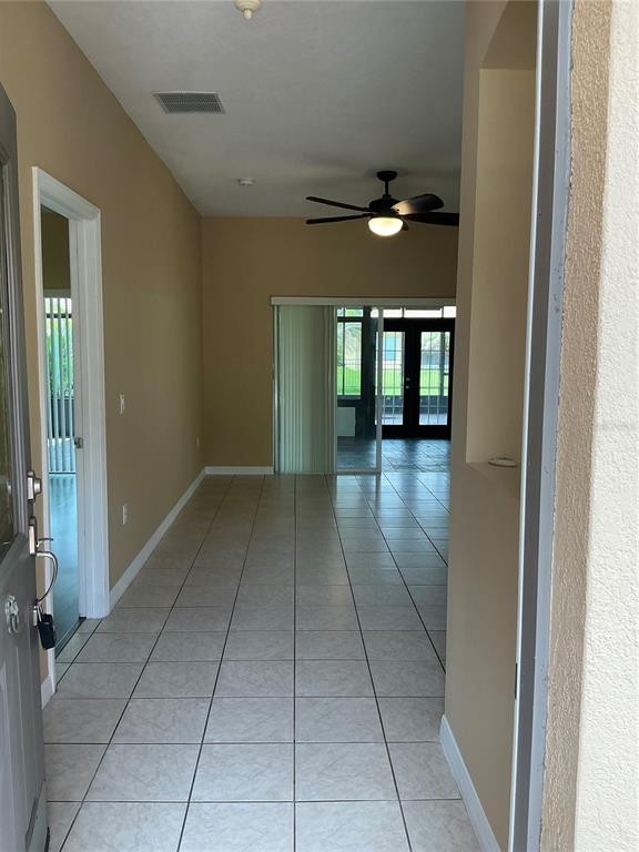 A tiled entryway leads into a living area with a ceiling fan and sliding doors — 3630 NORTHWOODS DRIVE, KISSIMMEE, FL