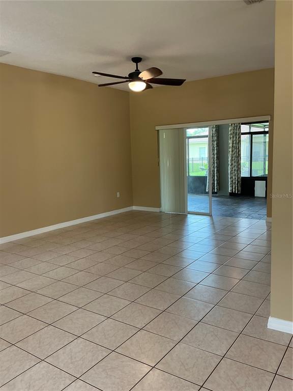A living room with tan walls, tiled floors, a ceiling fan, and sliding glass doors — 3630 NORTHWOODS DRIVE, KISSIMMEE, FL