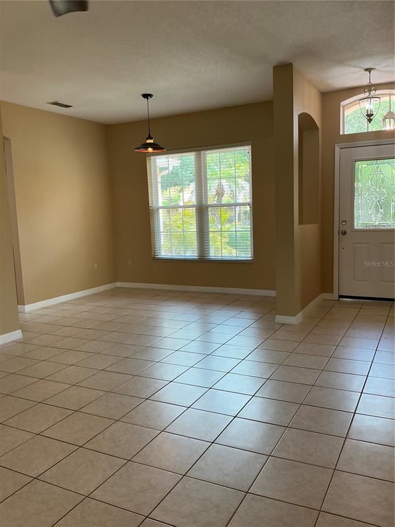 A room with beige walls, tile flooring, a window with blinds, and a front door — 3630 NORTHWOODS DRIVE, KISSIMMEE, FL