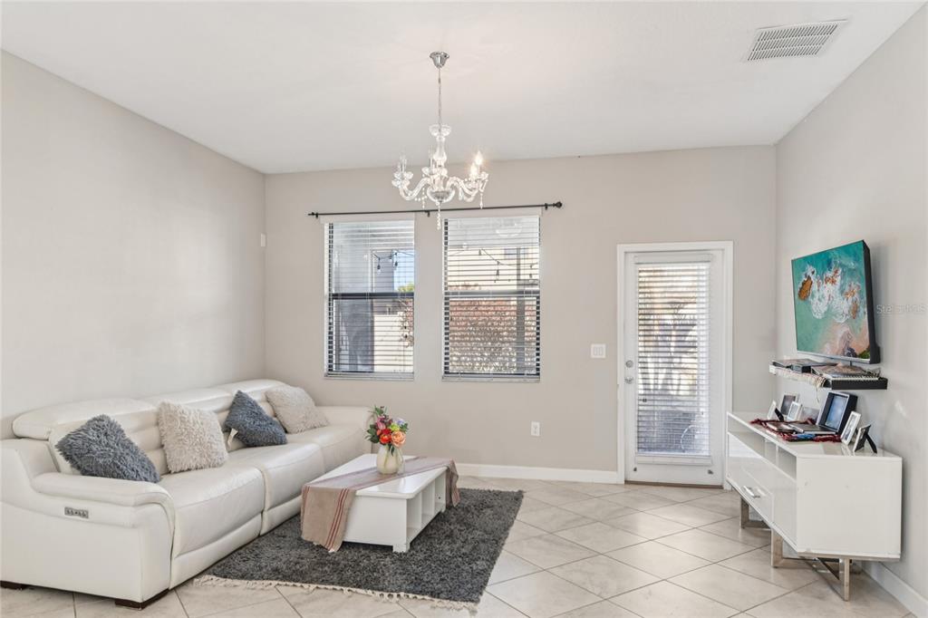 A living room features a white sofa, a chandelier, a coffee table, and a television — 1537 TALLULAH TERRACE, WESLEY CHAPEL, FL