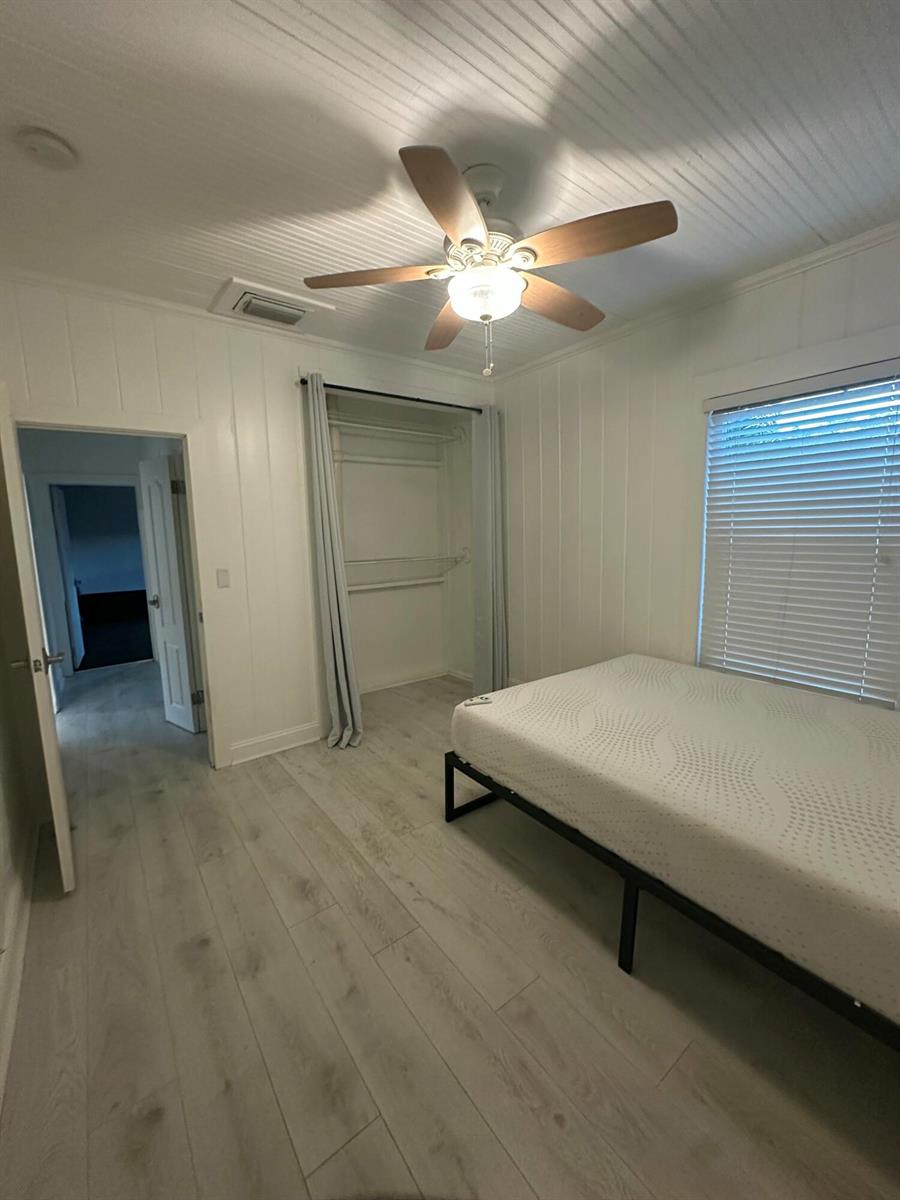 A bedroom with white paneled walls, light wood-look flooring, a ceiling fan, and a bed — 729 SE 2nd Avenue, Delray Beach FL 33483, DELRAY BEACH, FL