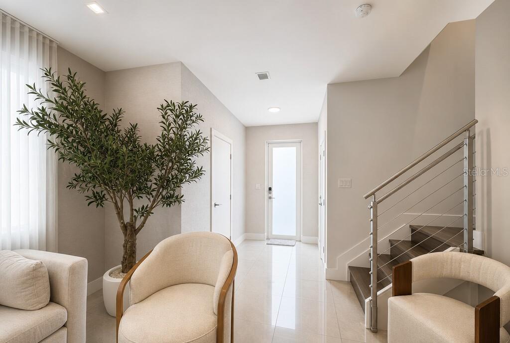A bright entryway features a staircase with metal railings, a potted tree, and two chairs — 10384 NW 67TH TER, DORAL, FL