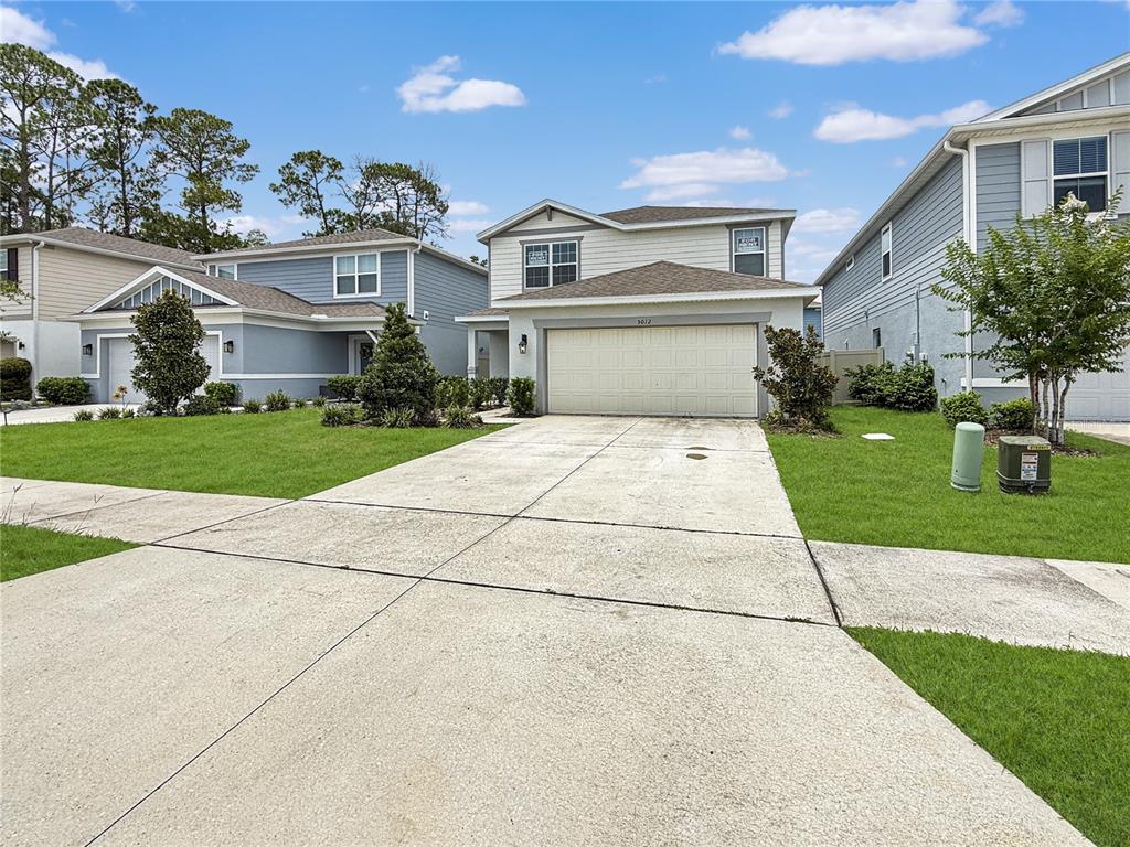 A two-story house with a beige exterior, a two-car garage, and a concrete driveway — 5012 BLUE HAMMOCK COURT, KISSIMMEE, FL