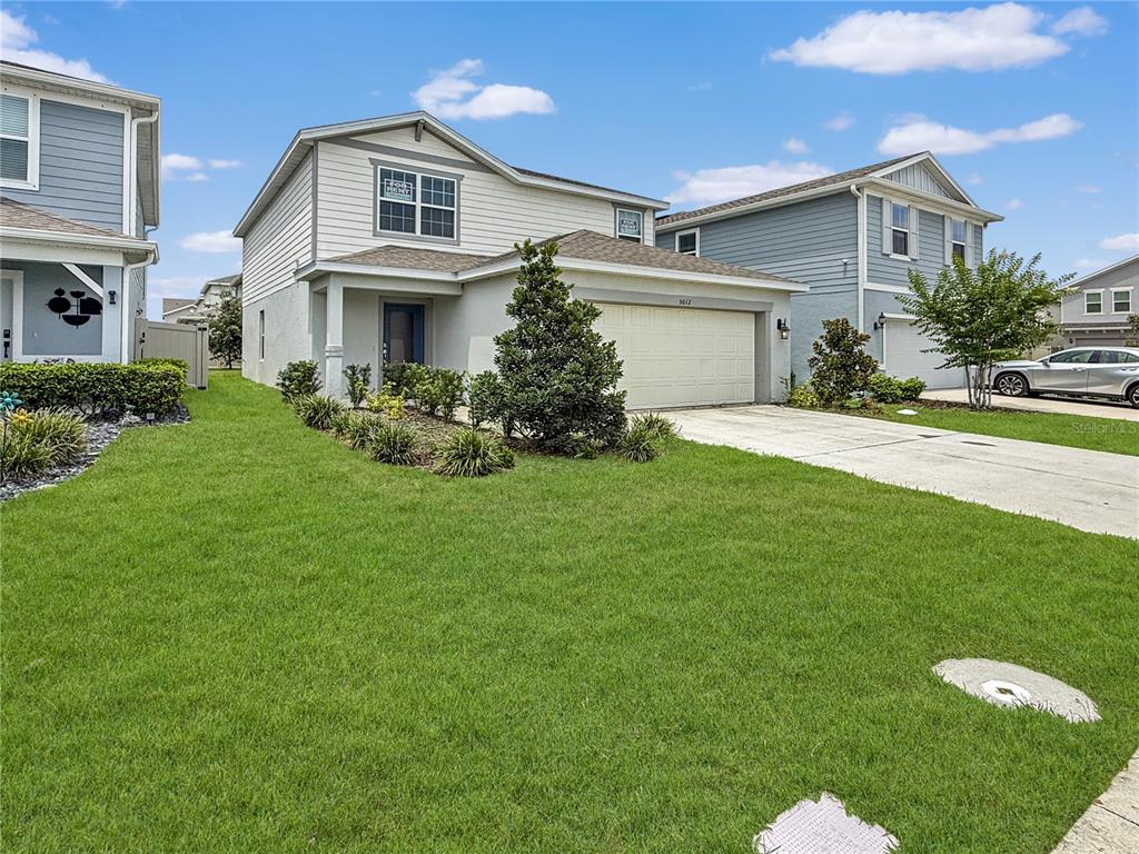 A two-story suburban house with a beige garage, light siding, and a front lawn — 5012 BLUE HAMMOCK COURT, KISSIMMEE, FL
