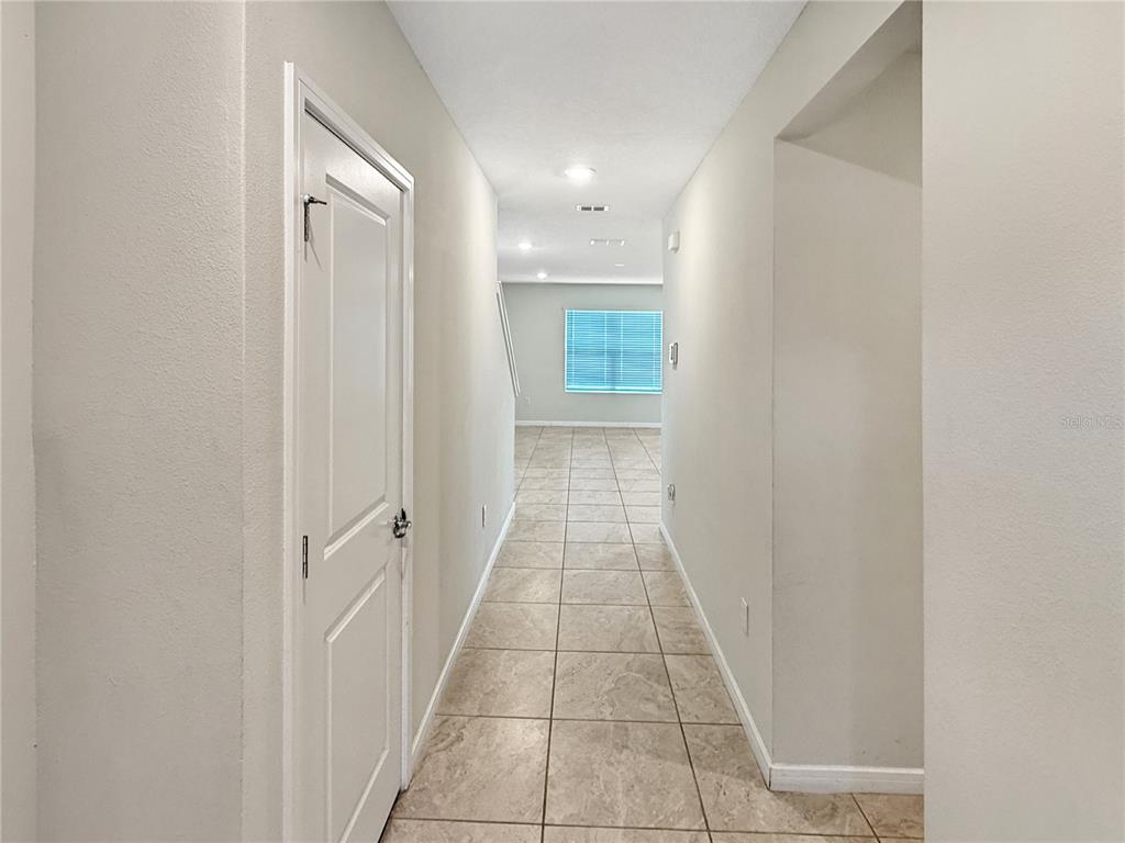 A hallway with light-colored tile flooring leads toward a room with a window — 5012 BLUE HAMMOCK COURT, KISSIMMEE, FL