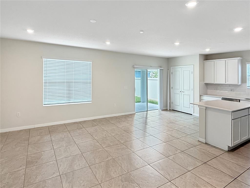 An open-concept living area features light-colored tile flooring, white cabinetry, and a sliding glass door — 5012 BLUE HAMMOCK COURT, KISSIMMEE, FL
