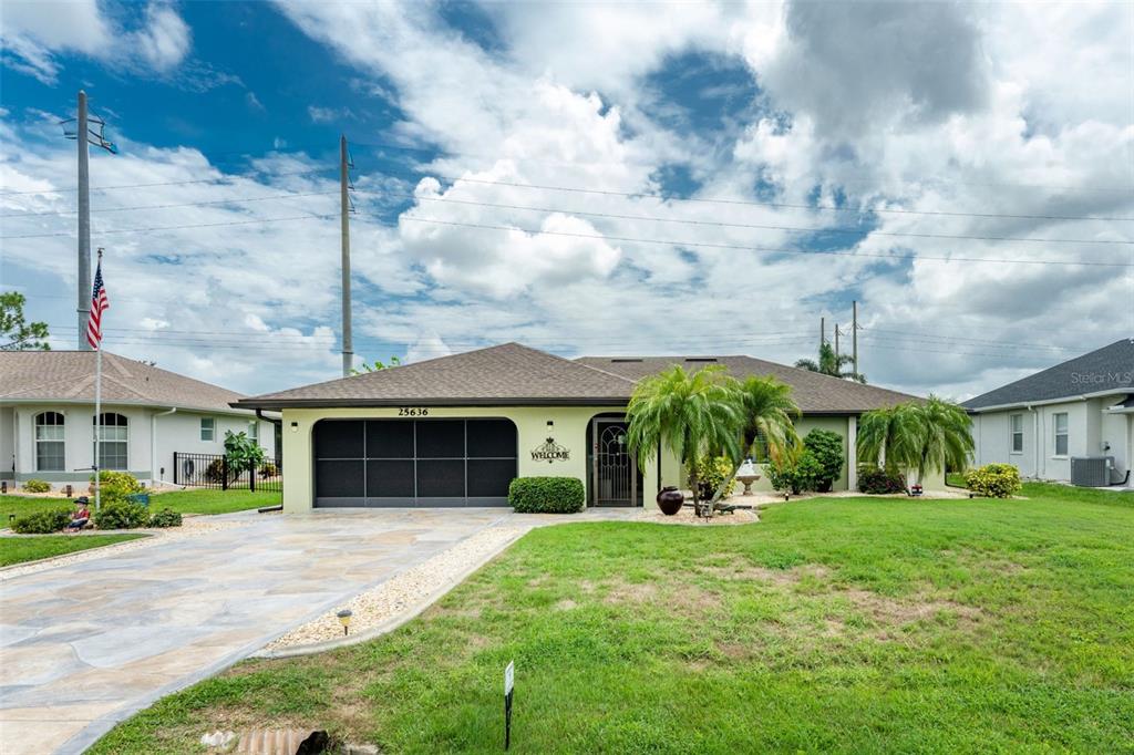 A single-story house with a light green exterior, a two-car garage, and a paved driveway — 25636 AYSEN DRIVE, PUNTA GORDA, FL