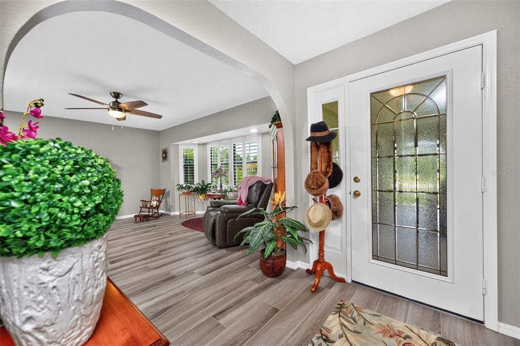 An entryway with wood-look tile flooring leads into a living room through an arched opening — 25636 AYSEN DRIVE, PUNTA GORDA, FL