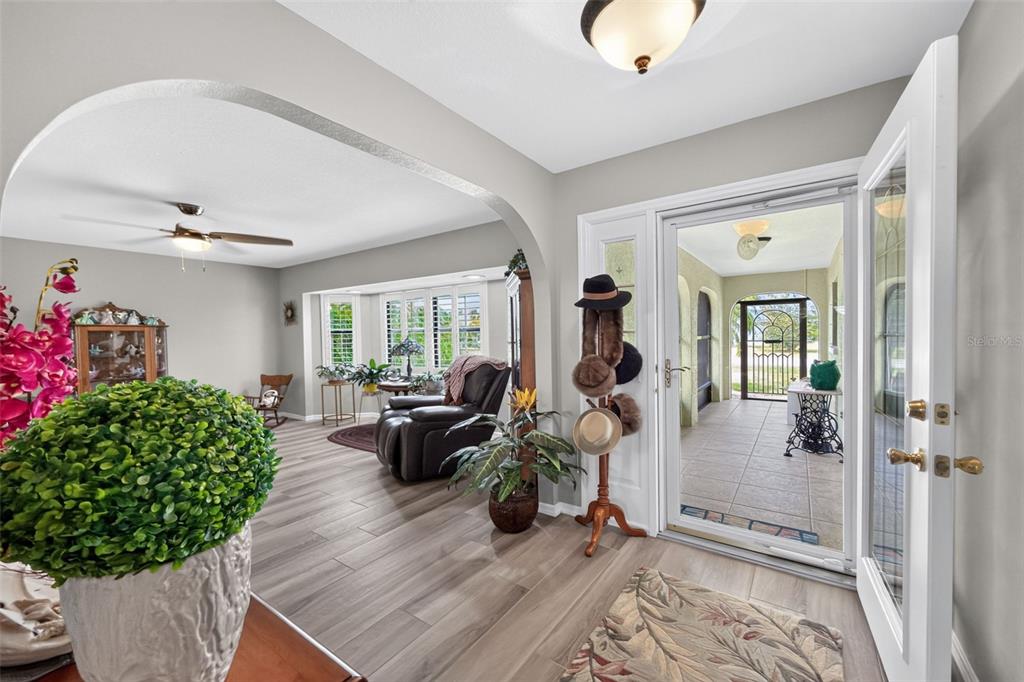 An entryway leads into a living room with wood-look flooring and an arched opening — 25636 AYSEN DRIVE, PUNTA GORDA, FL