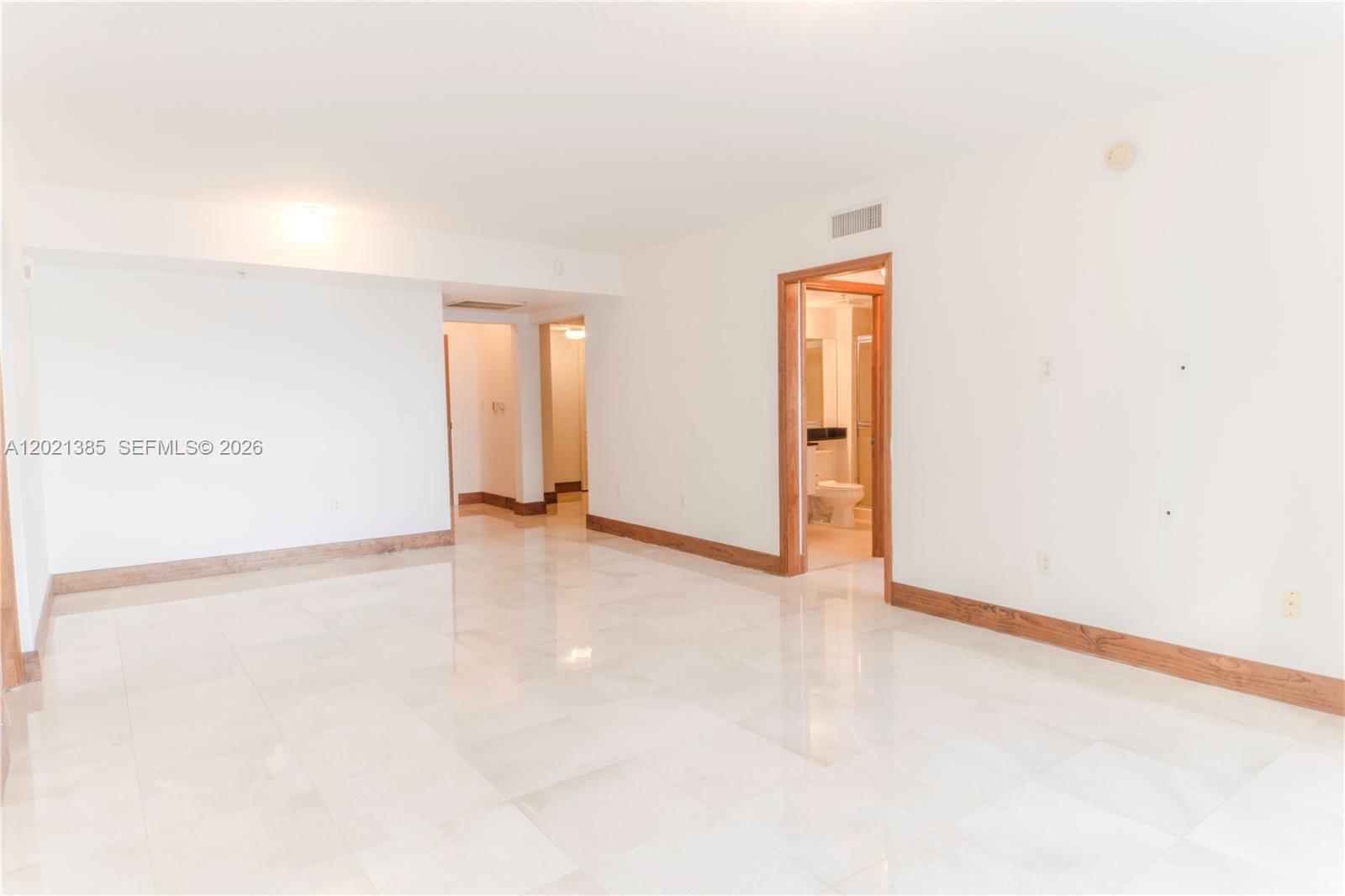 An empty room with white walls, light tile flooring, and wood baseboards features a doorway — 31 SE 5th St # 1208, Miami FL 33131, MIAMI, FL