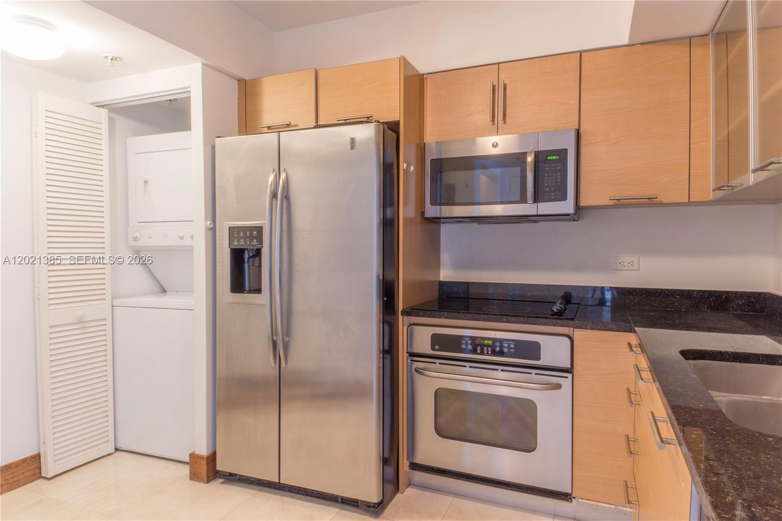 A kitchen features stainless steel appliances, light wood cabinets, and dark granite countertops — 31 SE 5th St # 1208, Miami FL 33131, MIAMI, FL