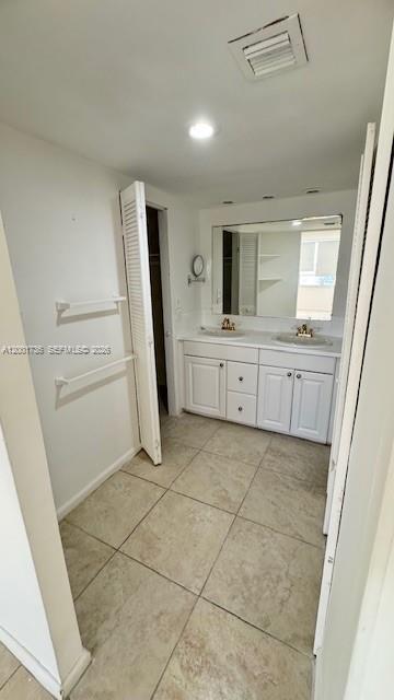 A bathroom with a double vanity, large mirror, tile flooring, and a closet with louvered doors — 2025 NE 164th St # 616, North Miami Beach FL 33162, NORTH MIAMI BEACH, FL
