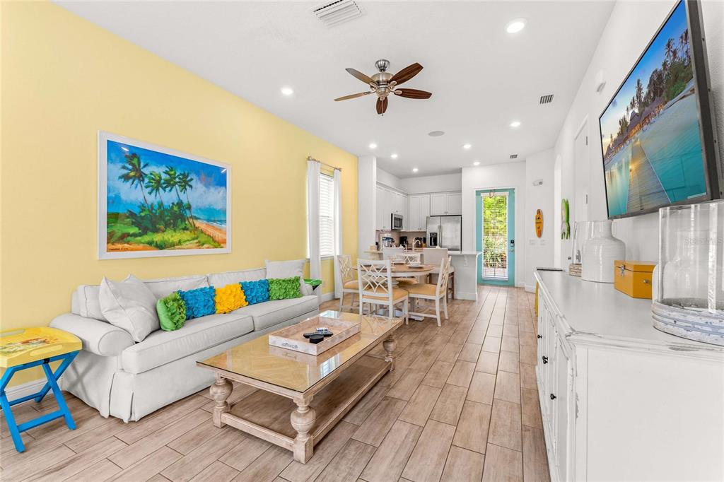 A living room and dining area feature yellow walls, a white sofa, and tile flooring — 8005 SAND BAR DRIVE, KISSIMMEE, FL