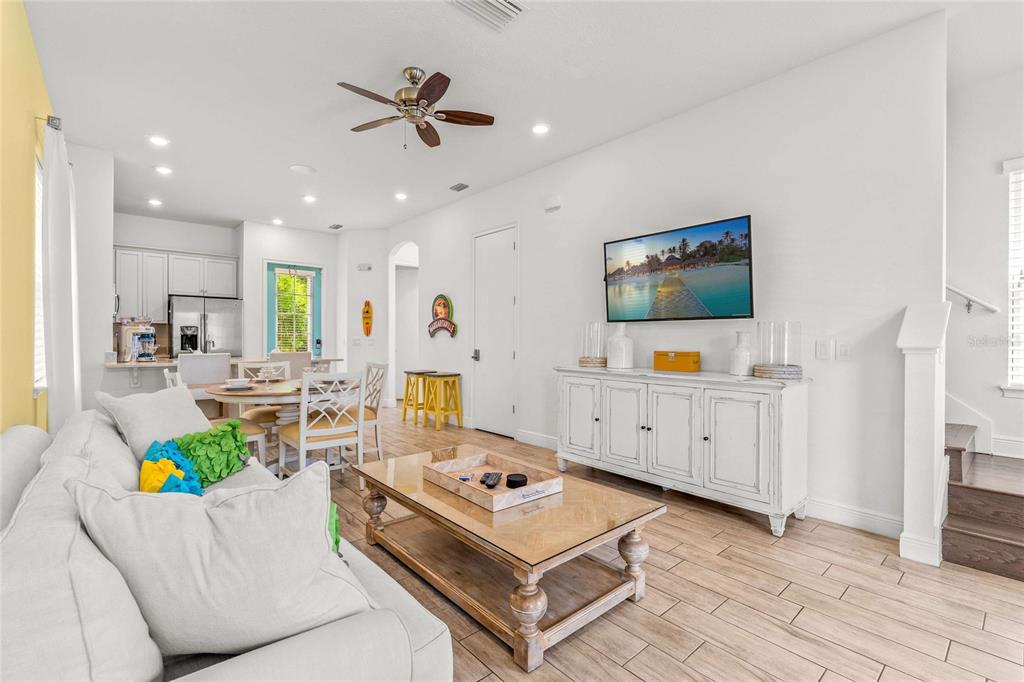 A bright living room features a white sofa, a glass-topped coffee table, and a television — 8005 SAND BAR DRIVE, KISSIMMEE, FL