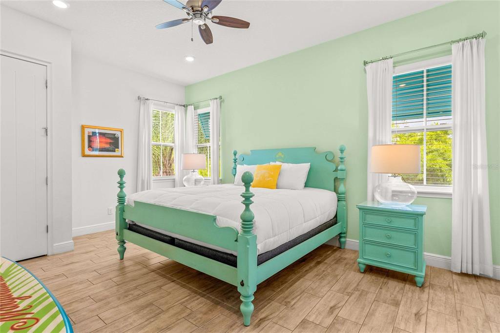 A bedroom features a light green wall, a turquoise bed frame, and wood-look tile flooring — 8005 SAND BAR DRIVE, KISSIMMEE, FL