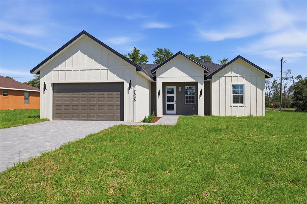 A modern single-story house with white board-and-batten siding, a gray garage, and a paved driveway — 2845 SW 172ND LANE ROAD, OCALA, FL